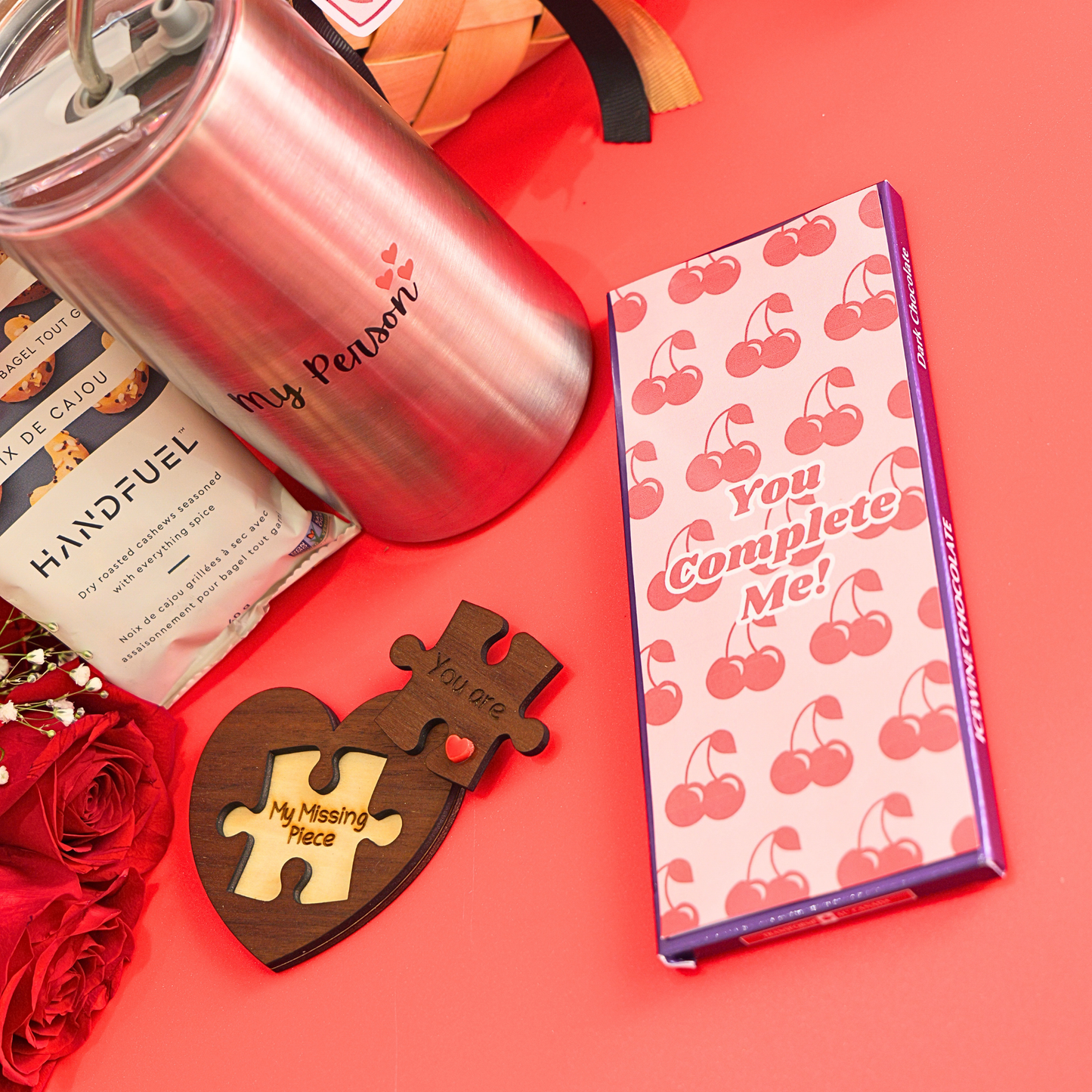 Valentine's Day-themed items including a pink tumbler, chocolate box, and wooden puzzle piece on a red background.