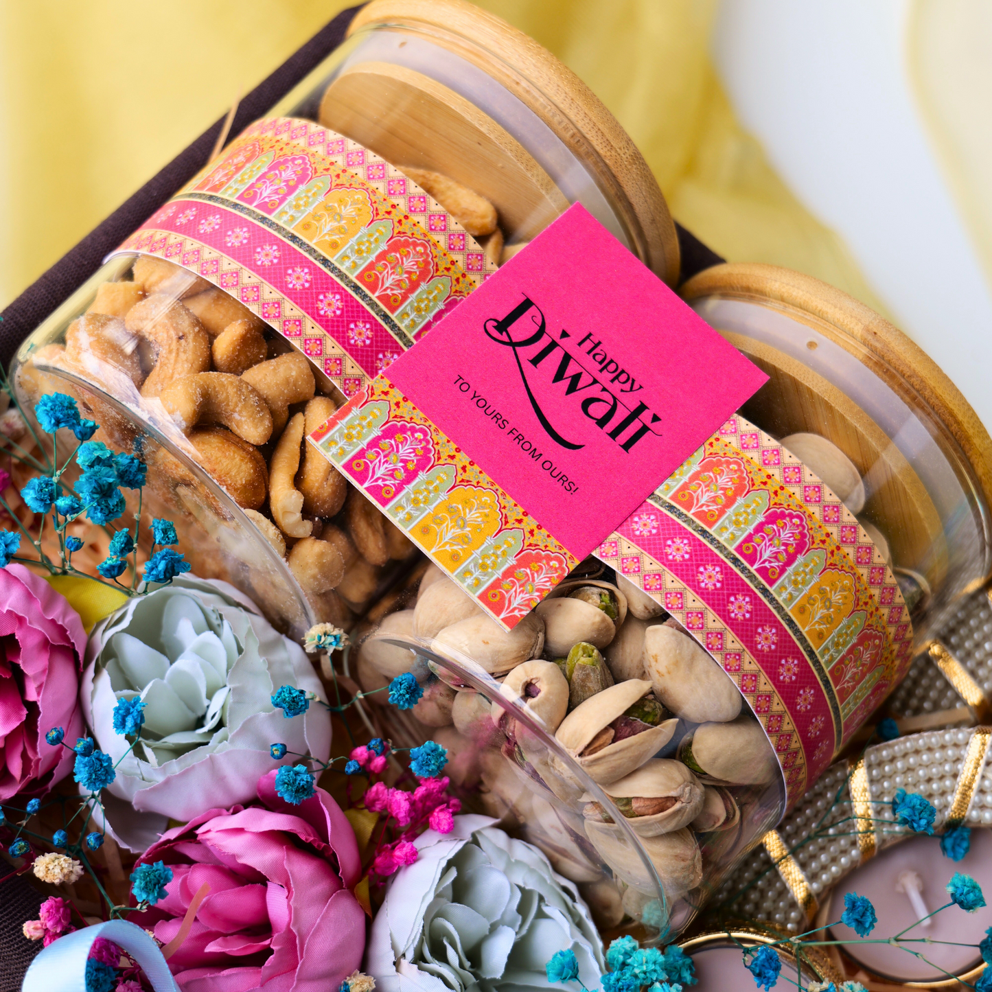 Gift jar of dry fruits with 'Happy Diwali' card, surrounded by flowers on a decorative background