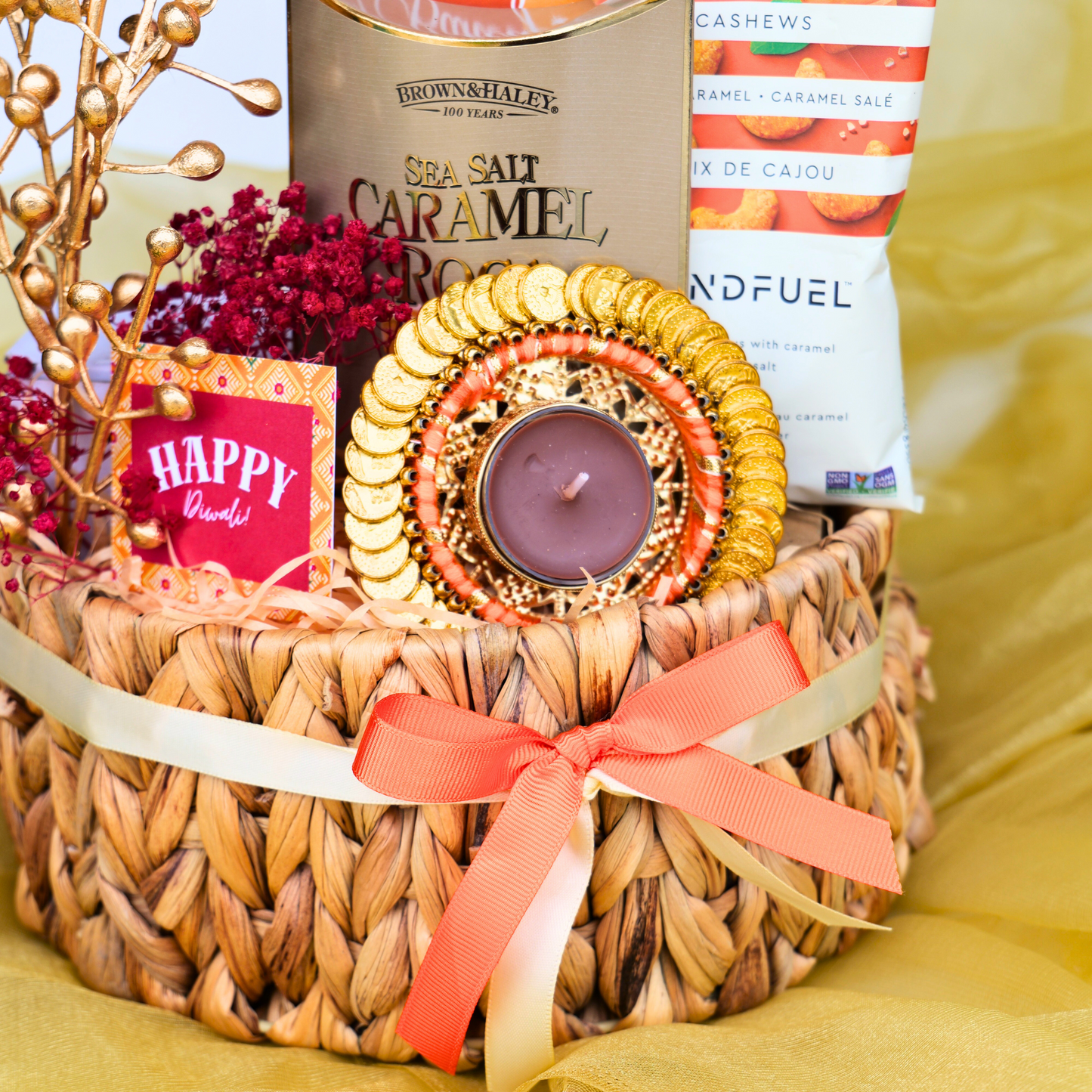 Gift basket with candles, snacks, and decorative items on a yellow surface