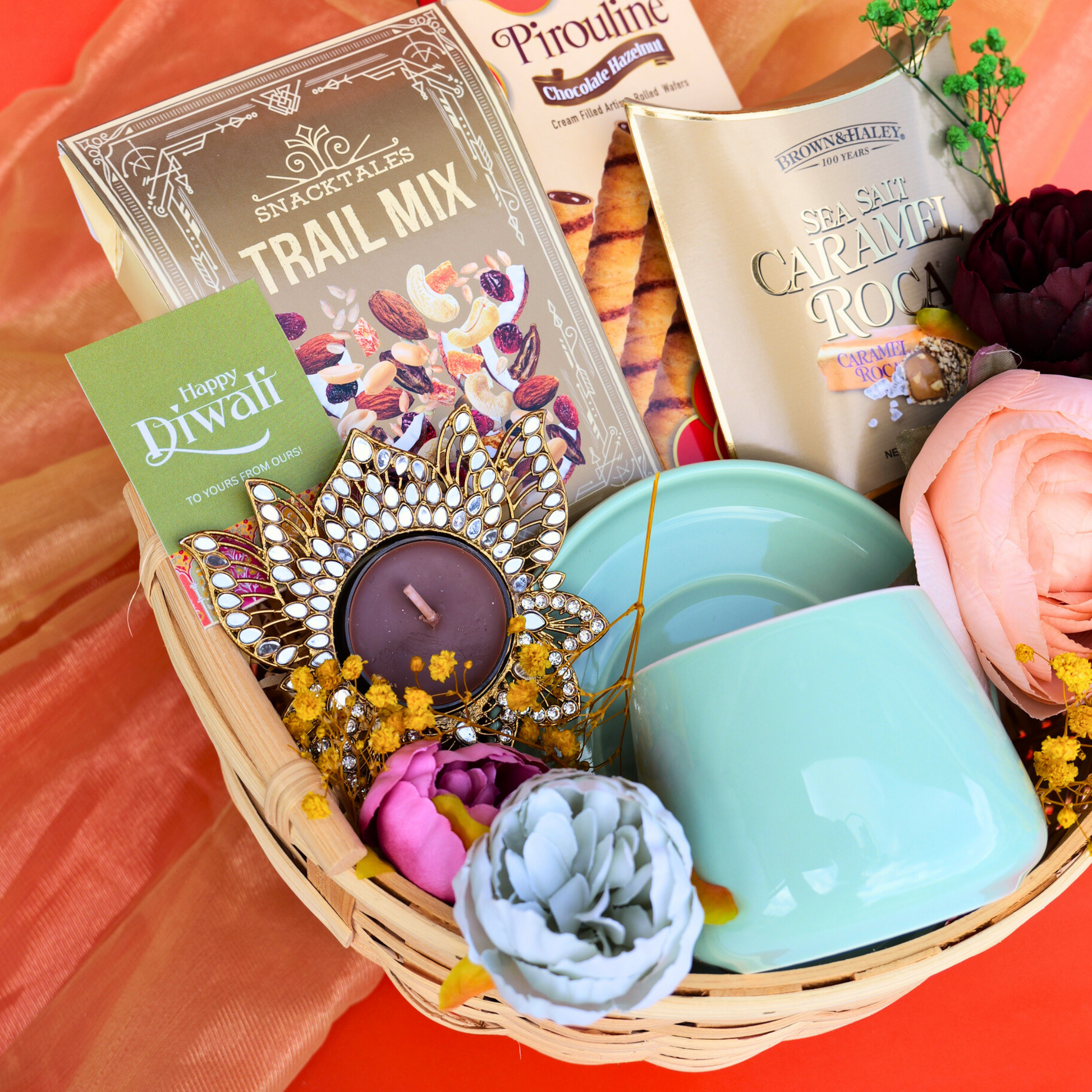 Gift basket with candles, flowers, and snacks on a colorful background