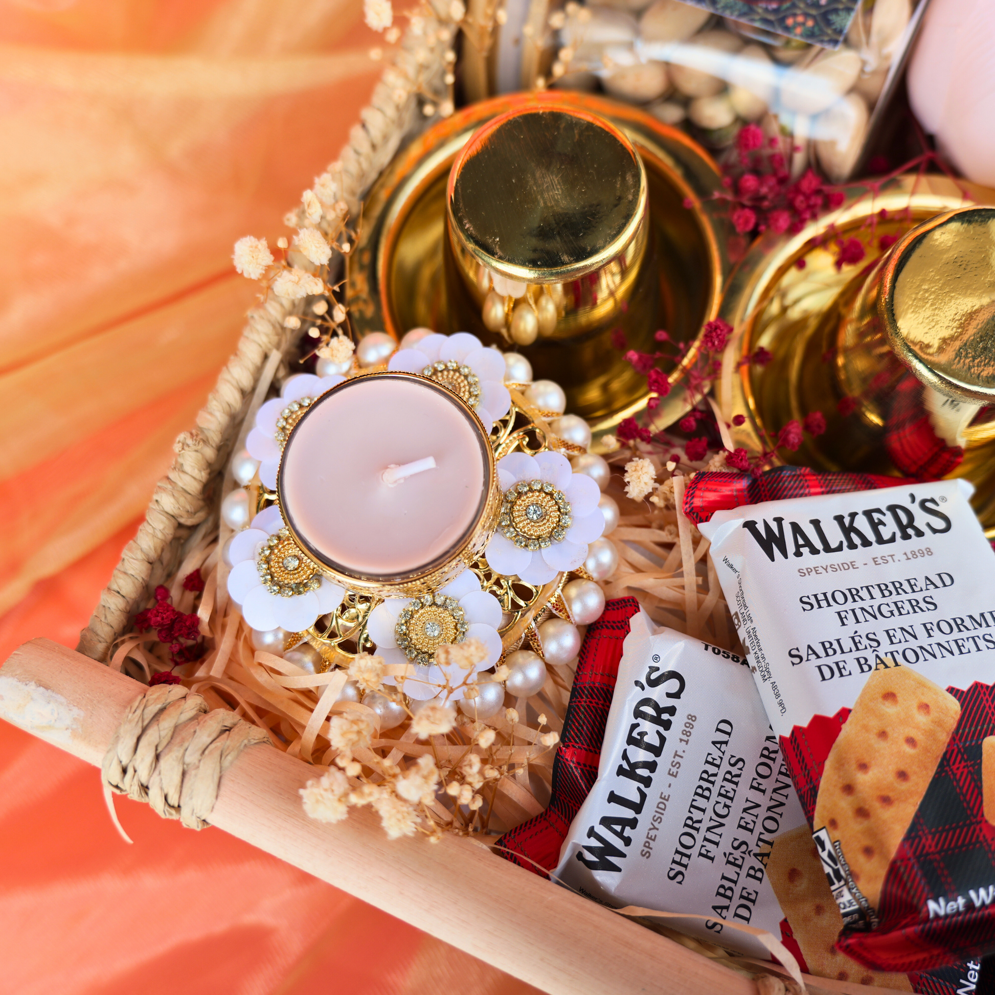 Decorative basket with pink fabric, flowers, and a card on an orange background