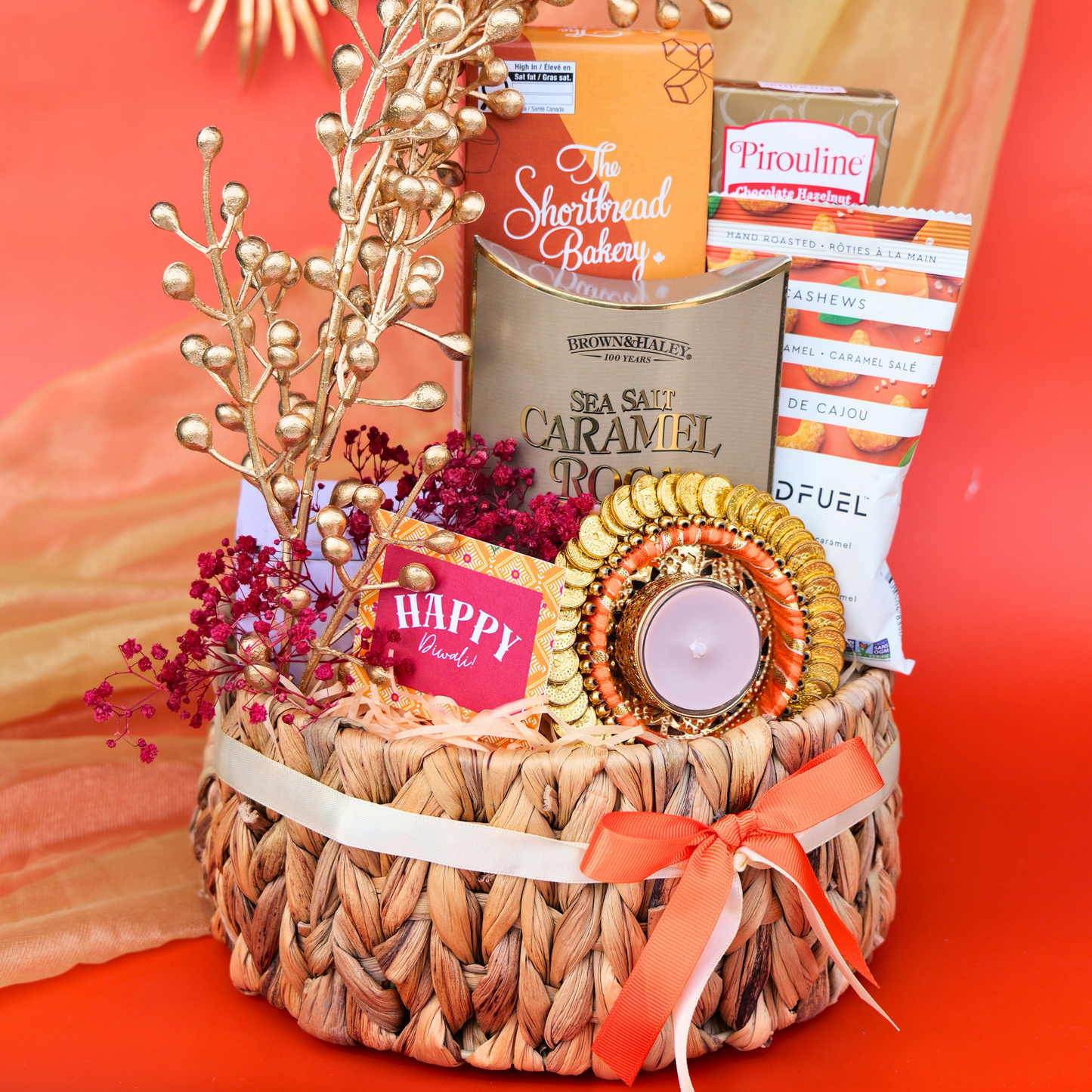 Gift basket with candles, chocolates, and decorative items on a table.