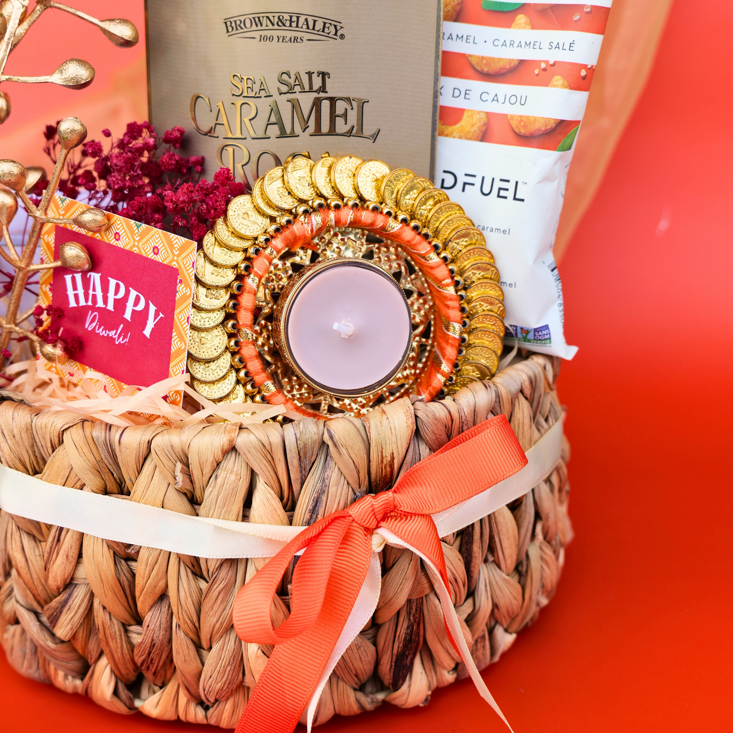 Gift basket with candles, flowers, and a bottle on an orange background