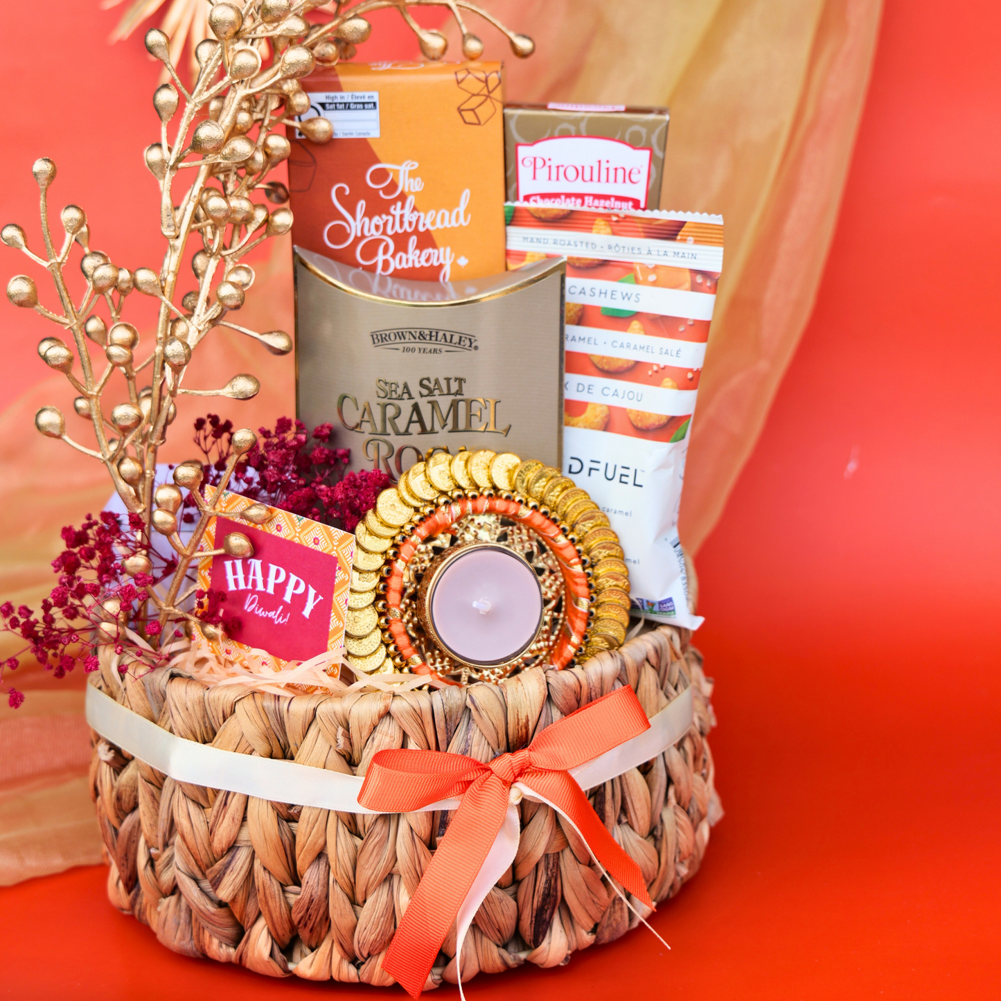 Gift basket with candles, snacks, and decorative items on a red background