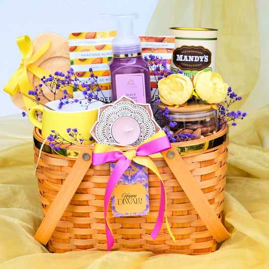 Gift basket with various items including a candle, flowers, and a bottle on a yellow fabric background.