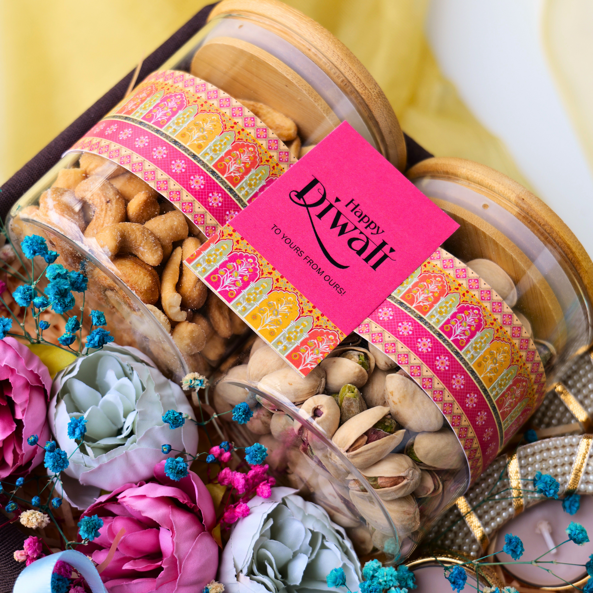Gift jar of dry fruits with 'Happy Diwali' card, surrounded by flowers on a decorative background