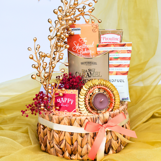 Gift basket with candles, flowers, and snacks on a yellow fabric background