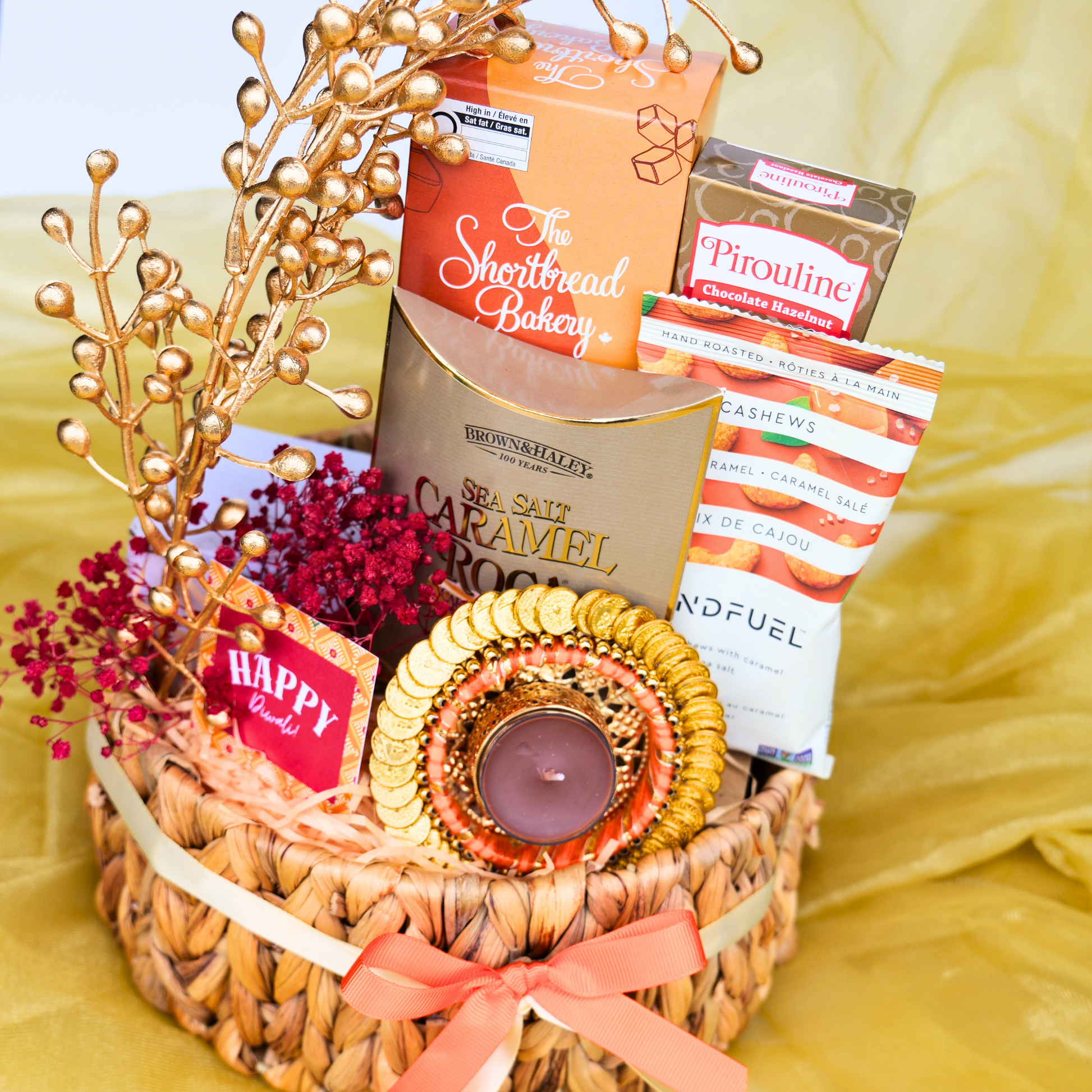 Gift basket with snacks, a candle, and decorative elements on a yellow background