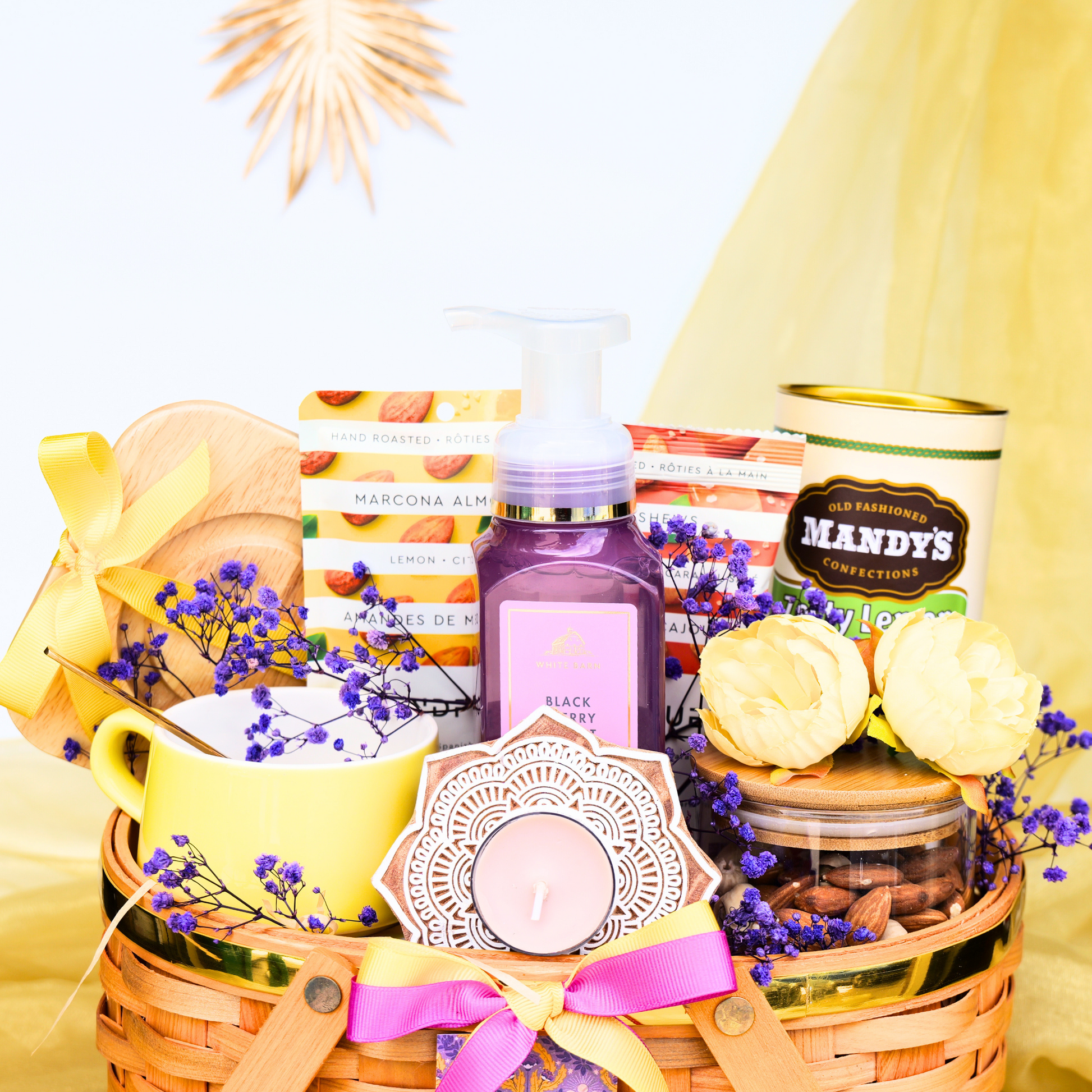Gift basket with various items including a bottle, mug, and candles on a white background