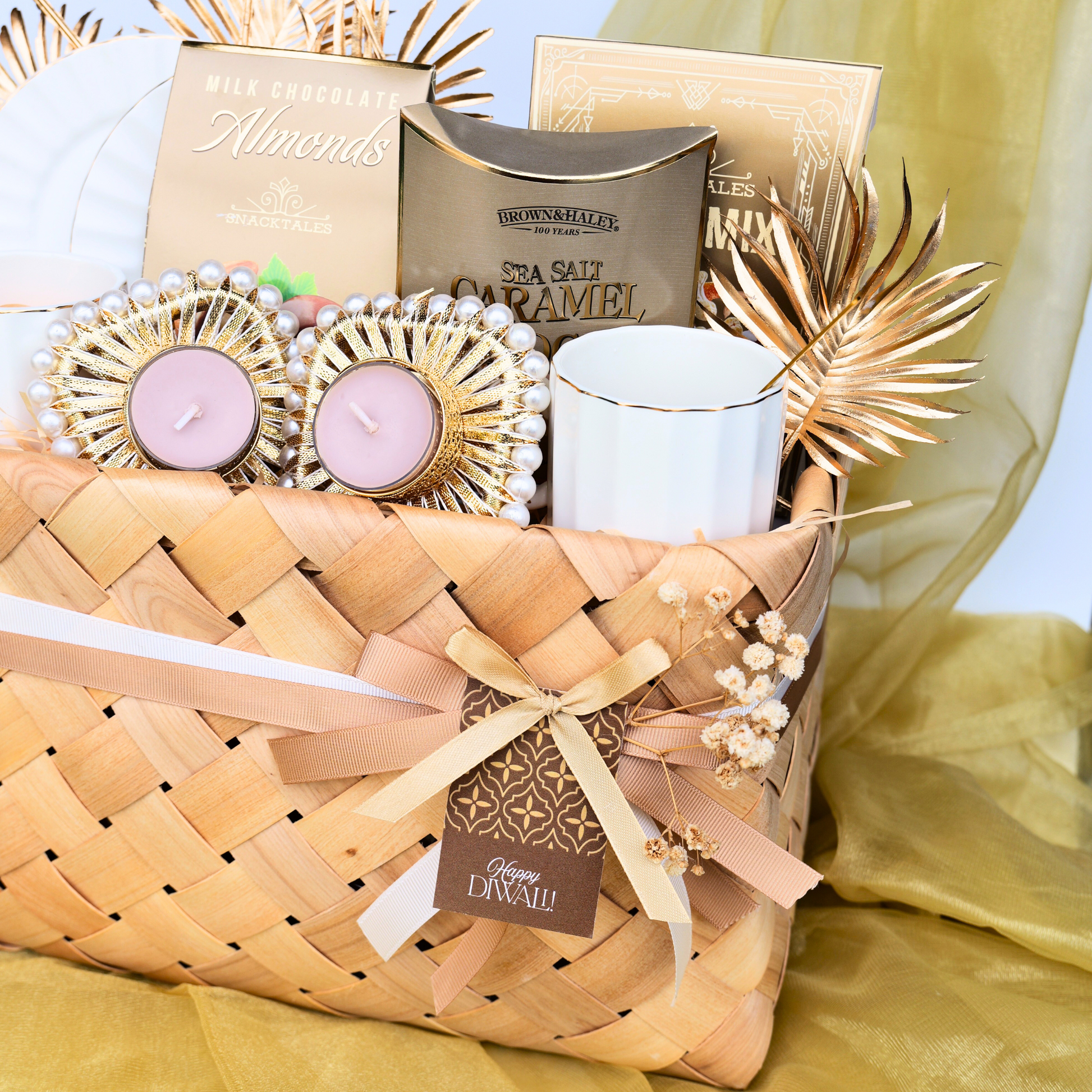 Gift basket with candles, tea, and decorative items on a yellow fabric background