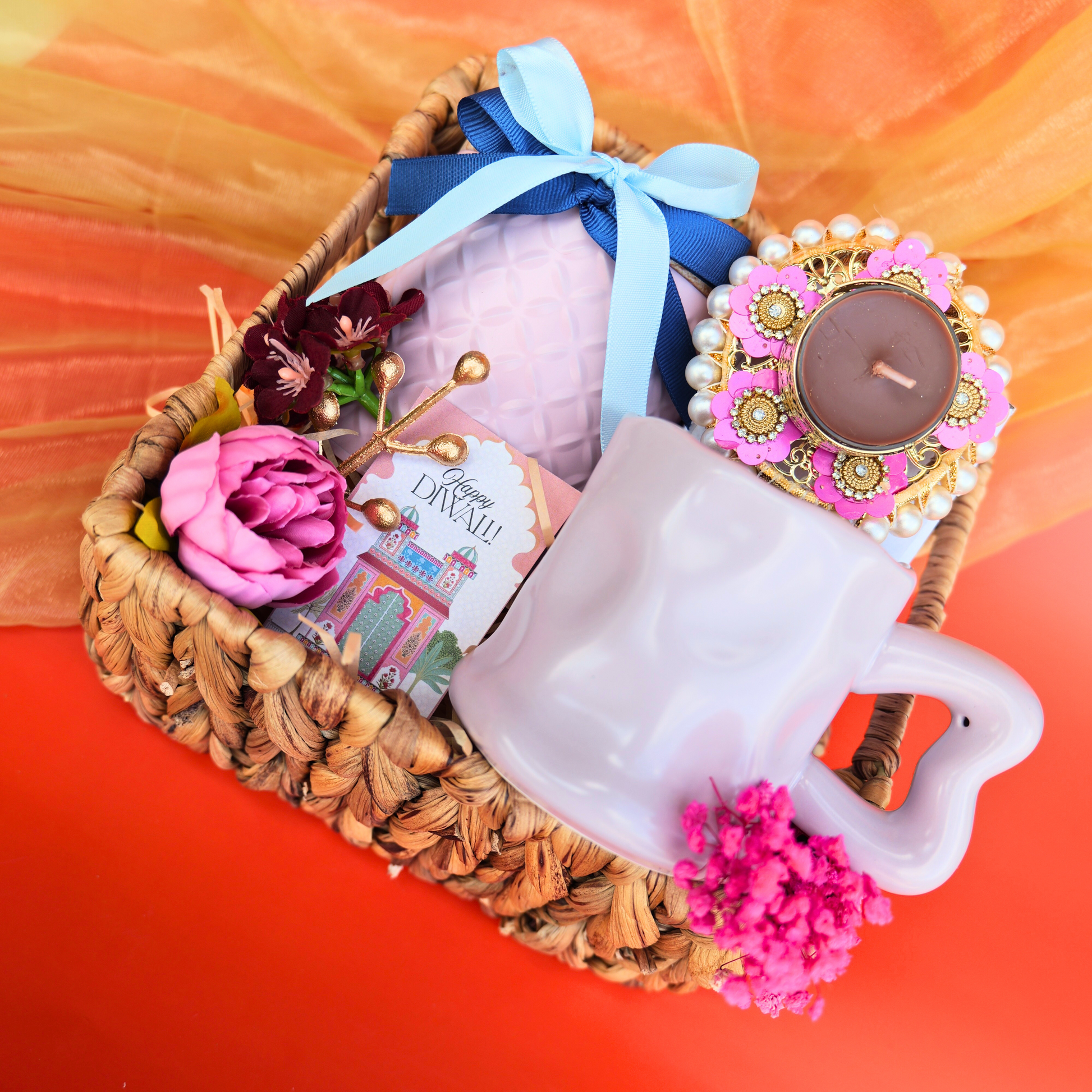 Decorative basket with a mug, candles, and decorative items on an orange background