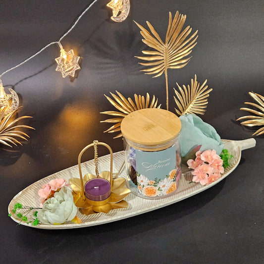 A festive hamper set including a jar of dates with nuts, a hanging lamp, and presented on a leaf platter, decorated with flowers and Christmas-themed decorations.