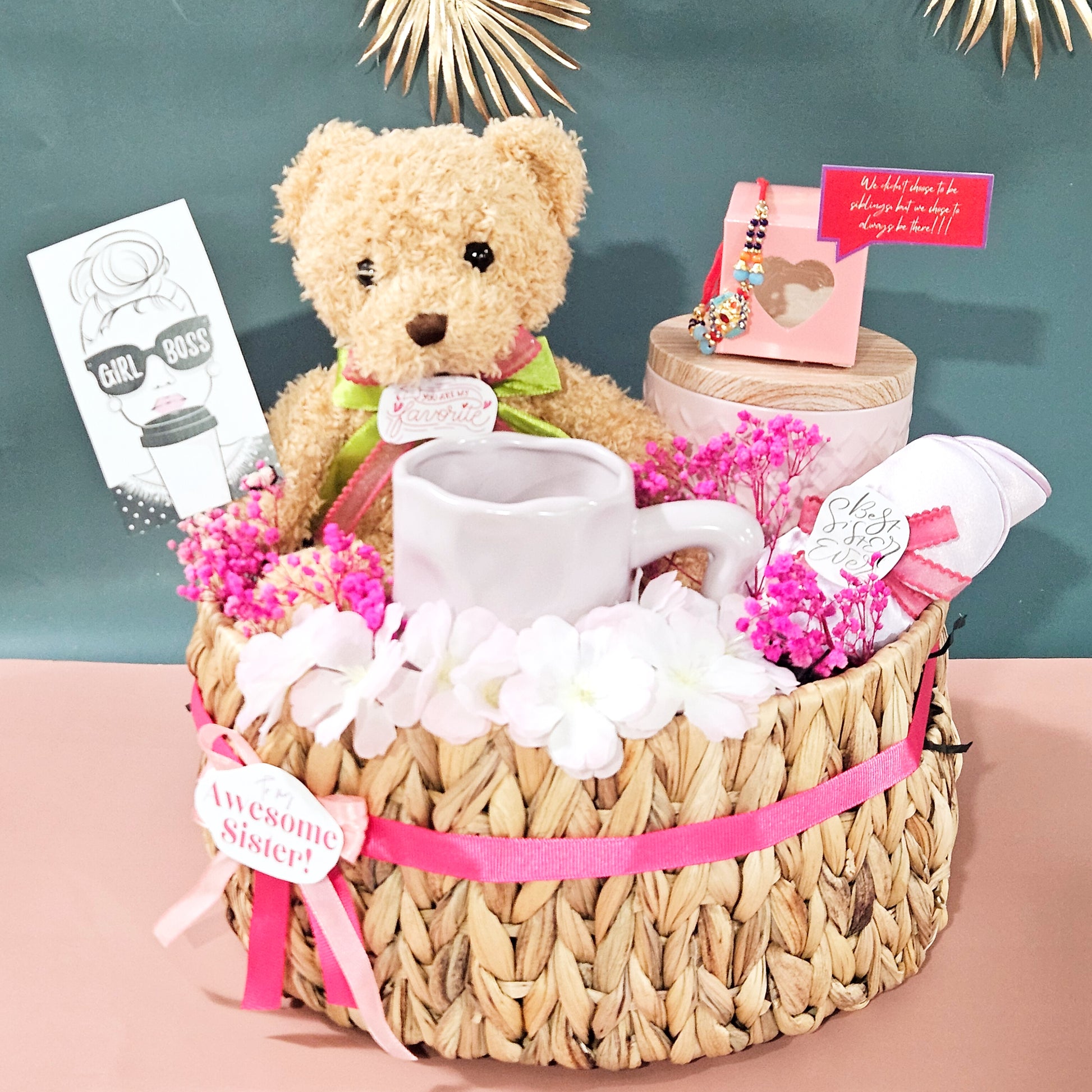 Gift basket with teddy bear, mug, and flowers on a pink surface