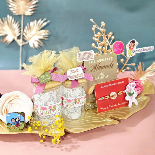 Gift set with chocolate almonds and decorative items on a pink surface with gold leaf accents.